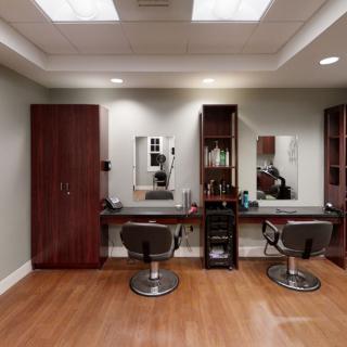 A modern hair salon interior with sleek chairs and mirrors, featuring wooden flooring and ample lighting.