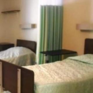 A hospital room featuring two beds separated by a curtain.