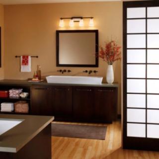 A modern, minimalist bathroom featuring wood flooring, large mirrors, and elegant lighting.
