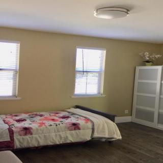 A cozy bedroom with a single bed, wardrobe, and ample natural light from two windows.