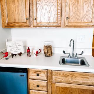 A kitchen countertop featuring wooden cabinets, a sink, decorative items, and a jar of cookies.