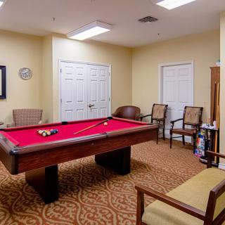 A cozy recreation room featuring a pool table with a red felt top, surrounded by comfortable seating.