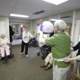 Elderly residents and caregivers engaging in a group ball game at a nursing home.