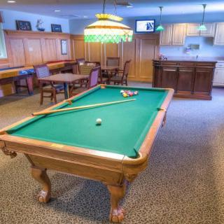 A cozy game room featuring a pool table and bar area.