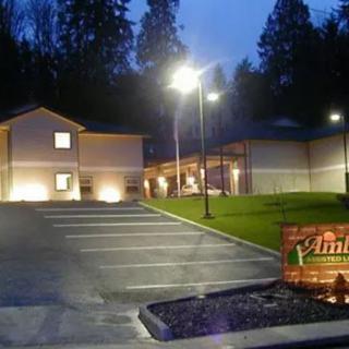 A well-lit building and parking lot surrounded by trees at night.