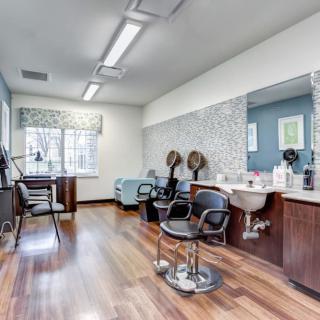 A modern hair salon with styling stations, chairs, and wooden flooring.