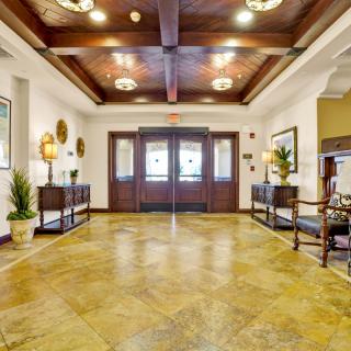 A spacious and elegantly decorated lobby area with a wooden ceiling and floor, featuring stylish furniture and potted plants.