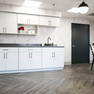 A modern kitchen with white cabinets and a sleek gray floor, showcasing minimalist design.