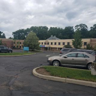A view of a parking area with a building in the background under a cloudy sky.