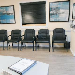 A clean and organized waiting room with black chairs and decorative artwork on the walls.