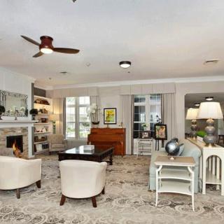 A spacious and elegantly designed living room featuring a fireplace, bookshelves, comfortable seating, and stylish decor.