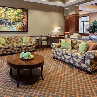 A cozy living room with patterned sofas and a central coffee table, featuring a colorful artwork on the wall.