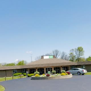 A modern building surrounded by greenery and a clear blue sky.