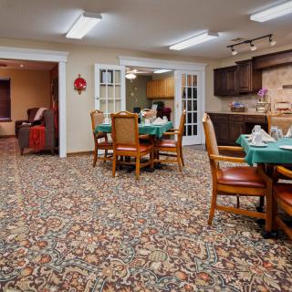 Cozy dining area with tables and chairs, adjacent to a kitchen space.