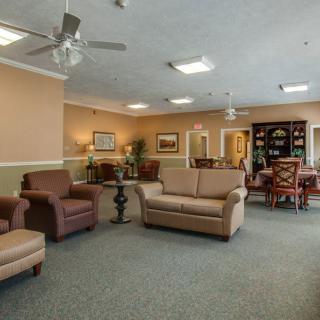 A spacious living room with comfortable seating, featuring sofas and chairs, decorated in warm tones.