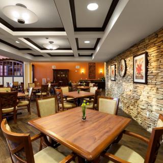 A cozy restaurant interior with neatly arranged tables and chairs, complemented by warm lighting and stylish wall decor.