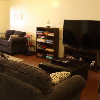 A cozy living room featuring a sofa set, a television, and a bookshelf filled with books.