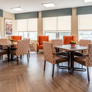 A cozy dining area featuring modern furniture with colorful chairs and natural light.