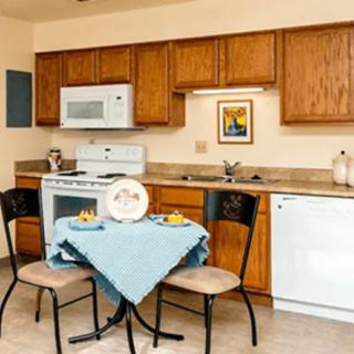 A cozy kitchen and dining area featuring wooden cabinets, a small table with two chairs, and modern appliances.