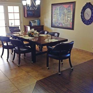 A dining room with a large table surrounded by chairs, a chandelier, and wall decor including a painting and mirror.