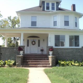 A large two-story house with a wraparound porch and a well-kept front yard.