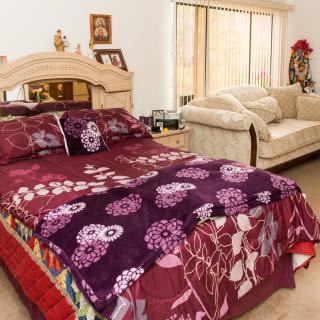 A cozy bedroom with a colorful floral bedspread and a comfortable couch in the corner.