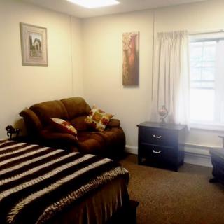 A cozy bedroom with a comfortable sofa and a bed, featuring soft lighting and simple decor.