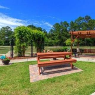 A serene outdoor area featuring a picnic table and a pergola surrounded by lush greenery.