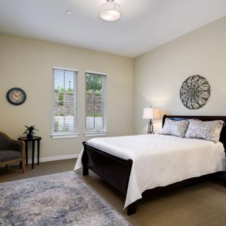A modern bedroom with a neatly made bed, decorative wall art, and stylish furnishings.