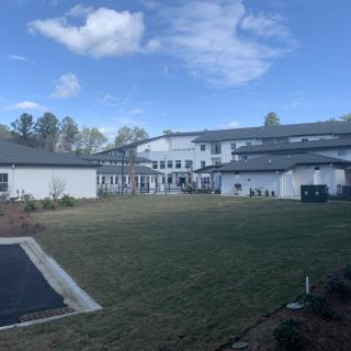 A residential building with a well-kept lawn under a partly cloudy sky.