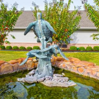A sculpture of a sea turtle and dolphin in a garden fountain.