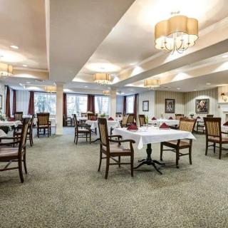 An elegantly decorated dining room with neatly arranged tables and chairs, illuminated by chandeliers.
