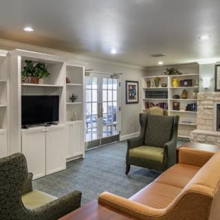 A cozy living room with comfortable seating and a television, surrounded by bookshelves and decorative elements.