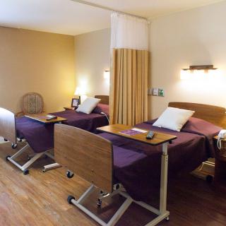 A hospital room with two patient beds separated by a privacy curtain.