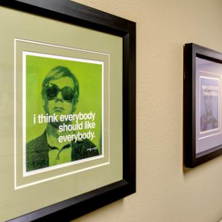A framed art piece featuring a green-toned portrait with the quote 'I think everybody should like everybody.'