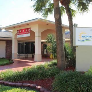 A view of a restaurant entrance with surrounding palm trees and signage.