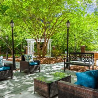 A tranquil outdoor patio surrounded by lush greenery, featuring comfortable seating and elegant design.