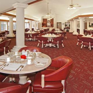 An elegant, empty dining room with neatly arranged tables and red chairs.
