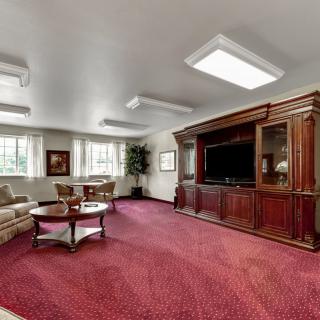 A spacious living room with a large entertainment center, plush carpeting, and comfortable seating arrangements.