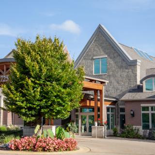 A charming residential building surrounded by lush greenery and vibrant flowers.