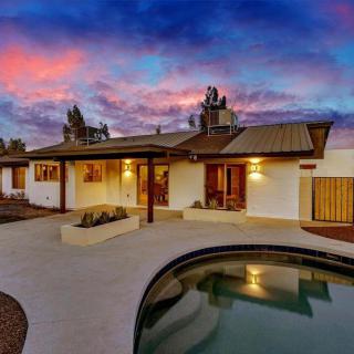 A beautiful house with a pool, set against a stunning sunset sky.