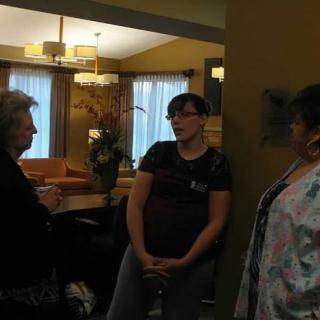 Three people engaged in conversation in a cozy living room setting.