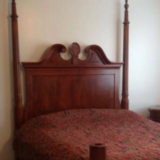 A classic four-poster wooden bed with an elegant headboard.