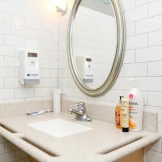 A clean bathroom sink with a mirror and various toiletries on the counter.
