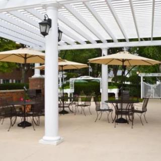 An outdoor patio area with a pergola, featuring tables and chairs under umbrellas.