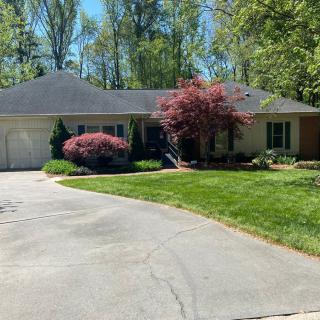 A suburban house with a driveway and well-maintained lawn surrounded by trees.