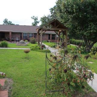 A quaint house with a lush garden, featuring a well-maintained lawn and charming gazebo.