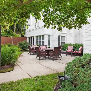 An inviting outdoor patio area with furniture surrounded by lush greenery.
