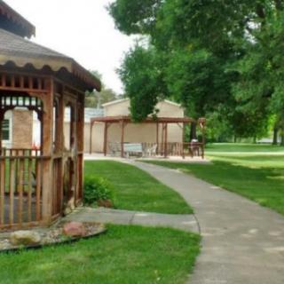 A scenic view of a park featuring a gazebo, pathway, and lush greenery.