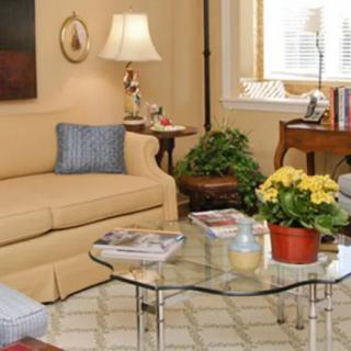 A cozy living room with a beige sofa, glass coffee table, and indoor plants.